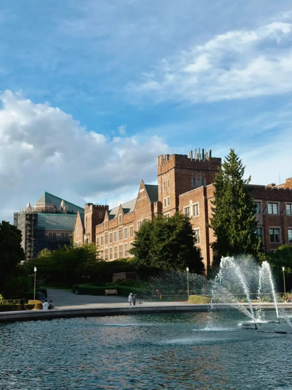 A fountain spraying water in a pond by brick buildings