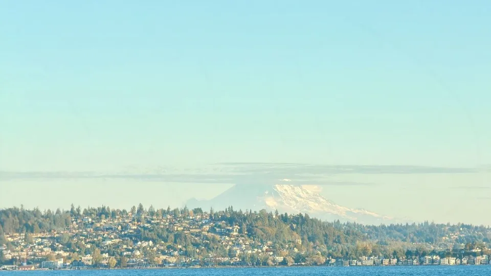 Mount Rainier above a tree-lined shore, seen across the water, Puget Sound, Washington