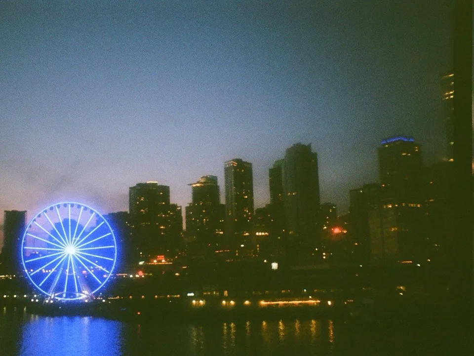 A lit wheel and city lights reflected in the waterfront at night, Seattle, Washington