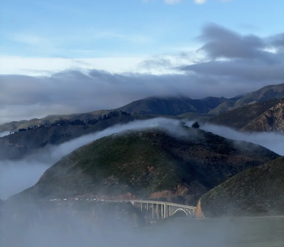 Fog rolling over coastal hills and a bridge, Big Sur, California